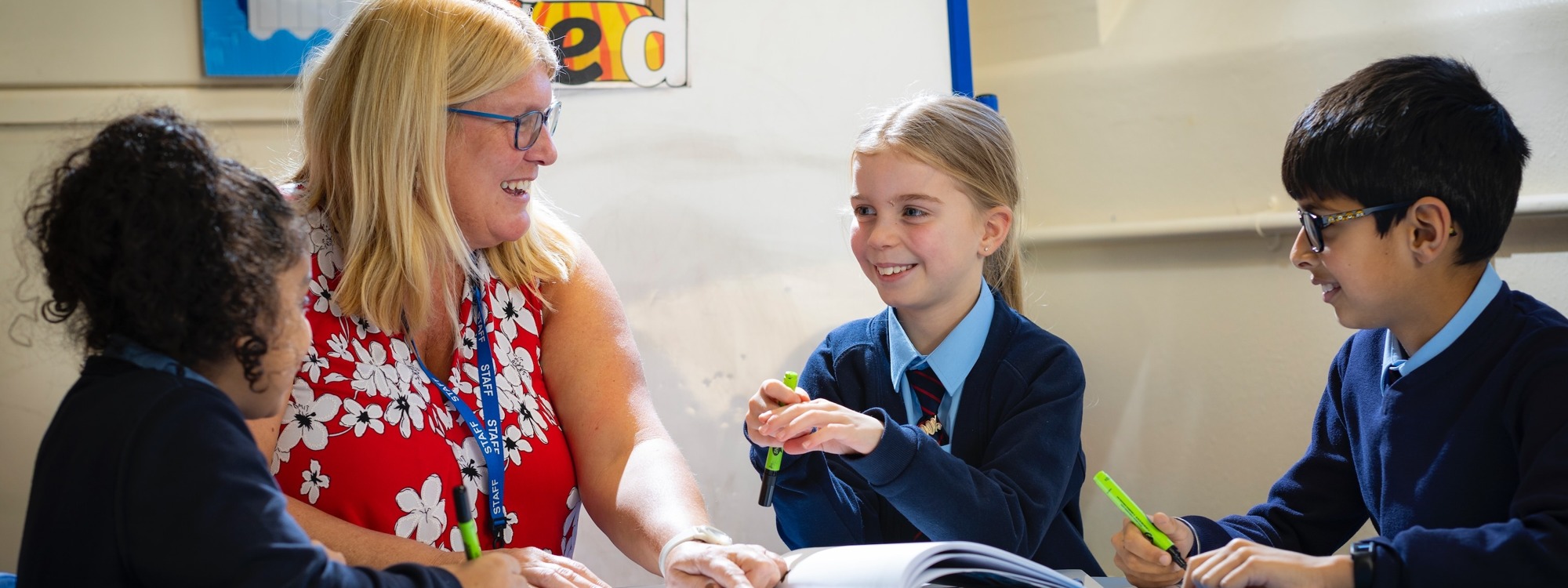 Lickey Hills School pupils looking at work with teacher in class